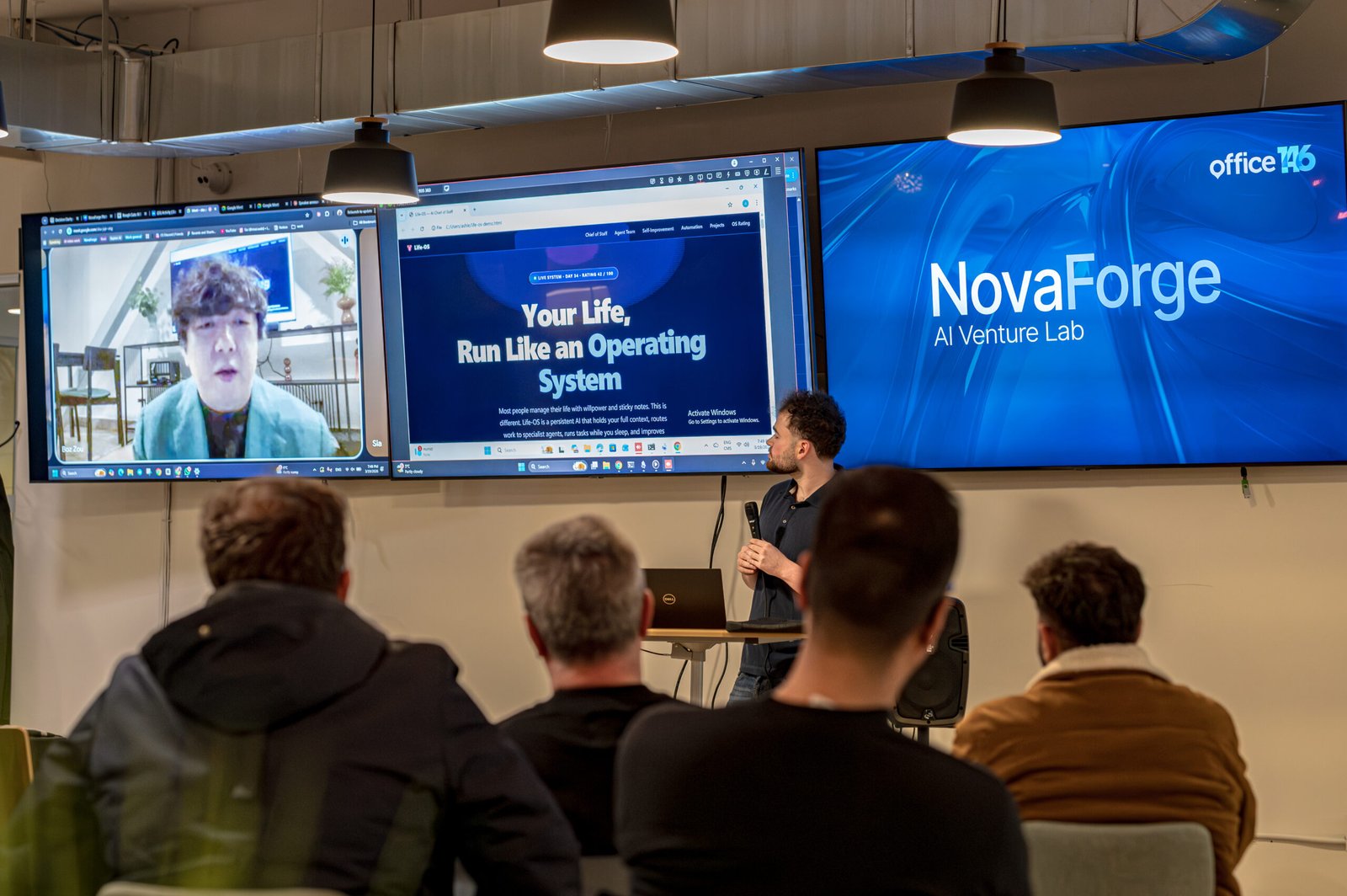 Presenter speaking to someone on a large screen online.