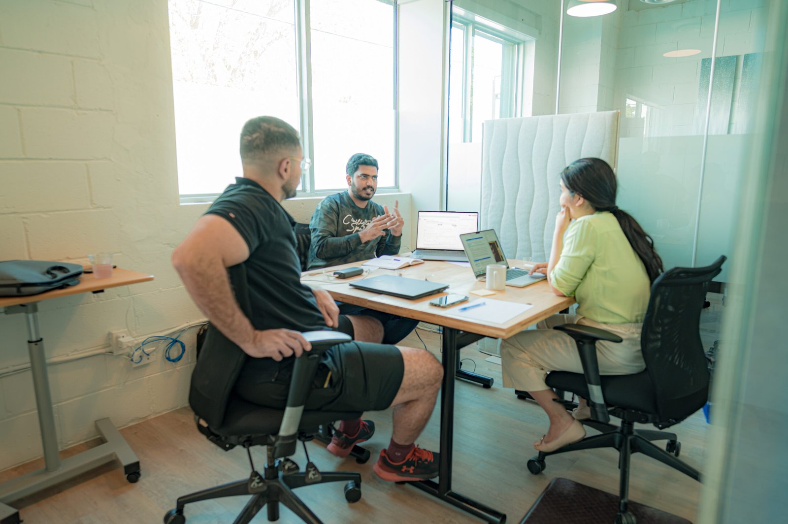 Three people working together in a meeting room.
