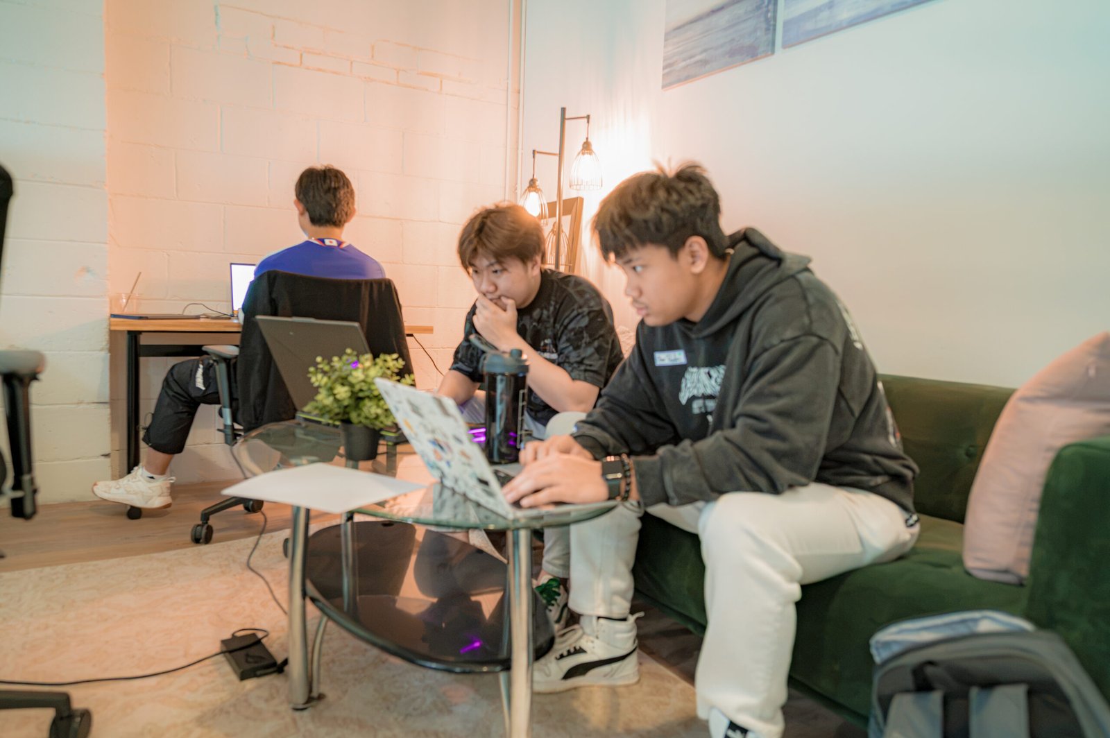 Two people focused on a computer as someone works behind them.