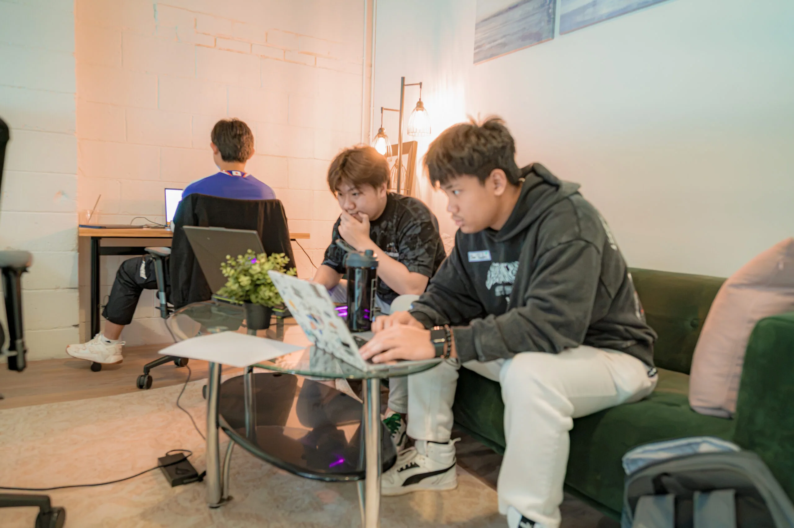 Two people focused on a computer as someone works behind them.