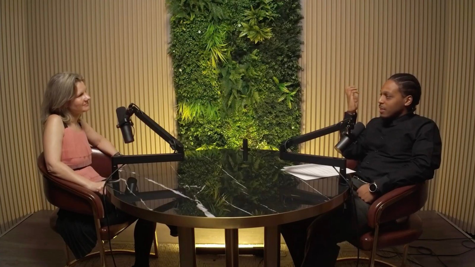 Two people speaking together in a podcast environment.