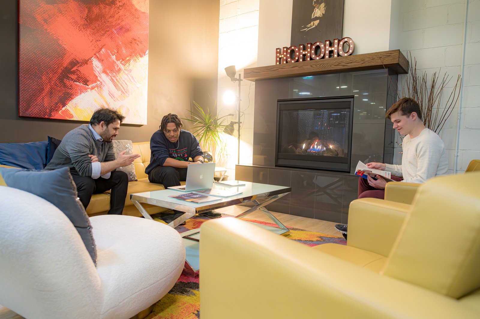 Three people sitting around the fireplace lounge.